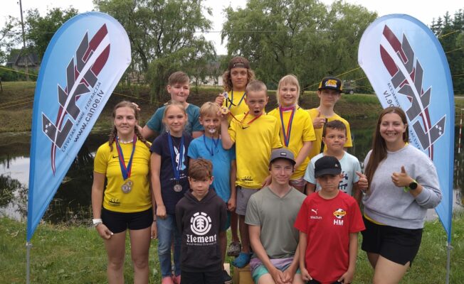 Bērni un trenere pēc sacensībām ar medaļām